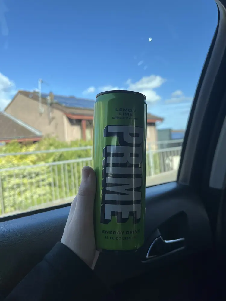 A can of PRIME Lemon Lime energy drink held up in the sunshine
